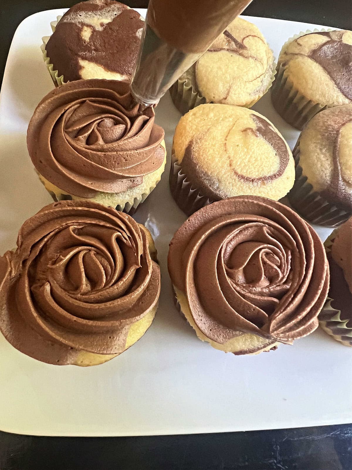 Piping rose swirls onto the marble cupcakes using a 2D piping tip.