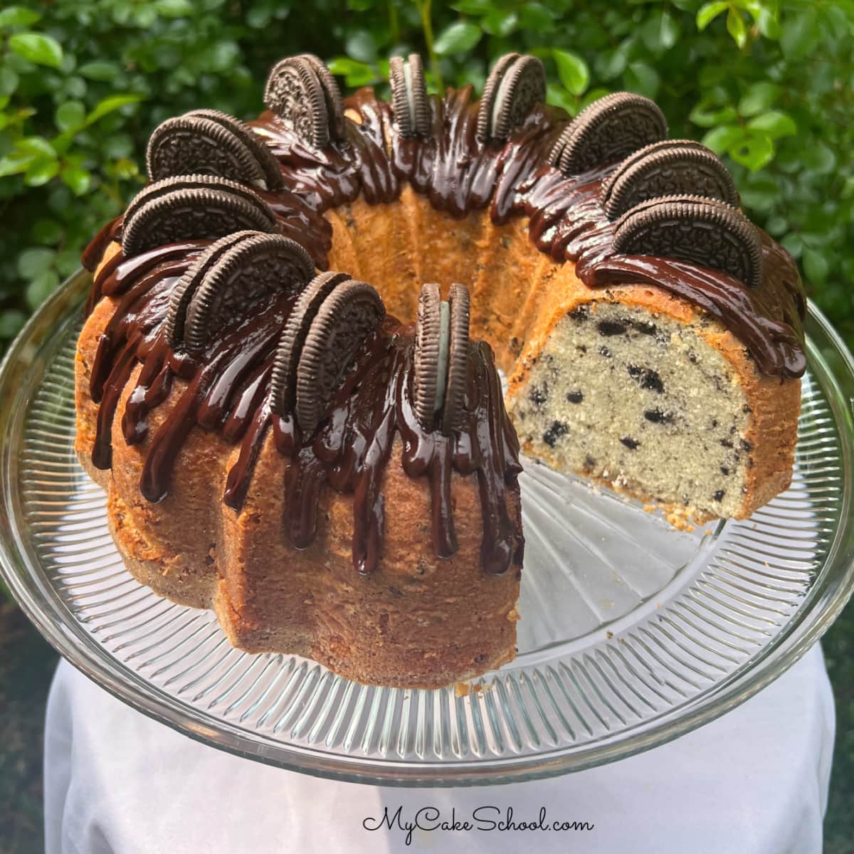 Oreo Pound Cake, topped with chocolate glaze and Oreos, on a cake pedestal.