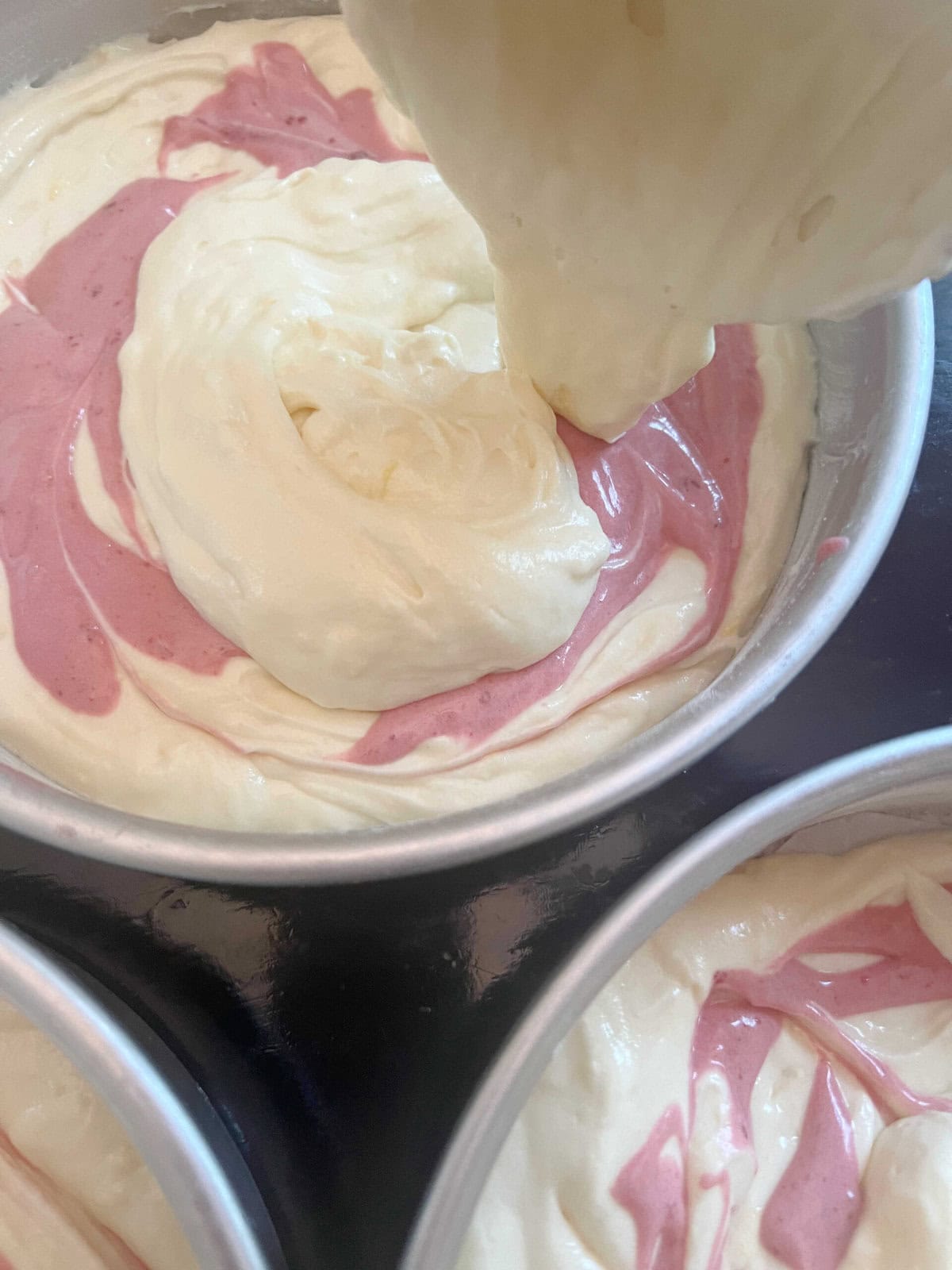 Filling the three prepared pans, alternating between lemon and raspberry cake batter.
