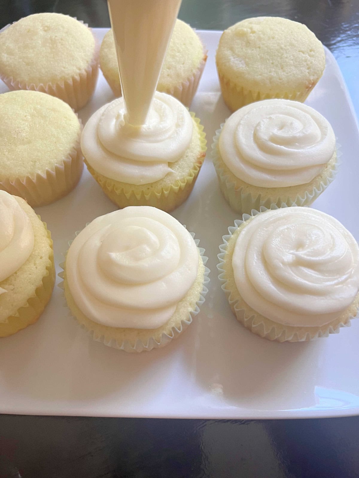 Frosting the lime cupcakes with coconut cream cheese frosting.