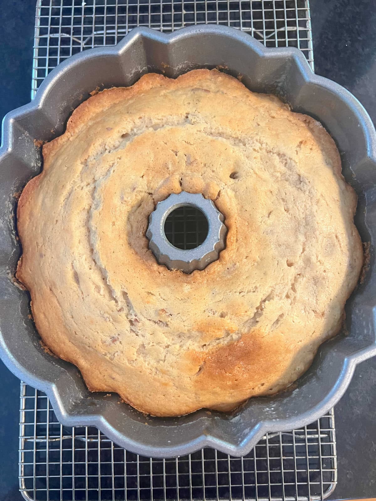 Freshly baked Banana Nut Cake cooling in a bundt pan on cooling rack.