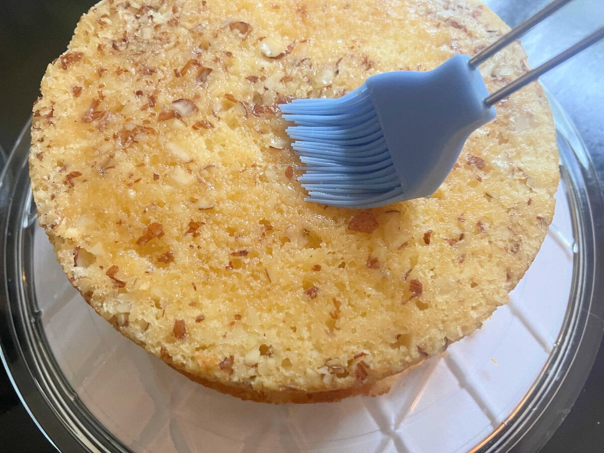 Brushing the Amaretto Cake layer with simple syrup.