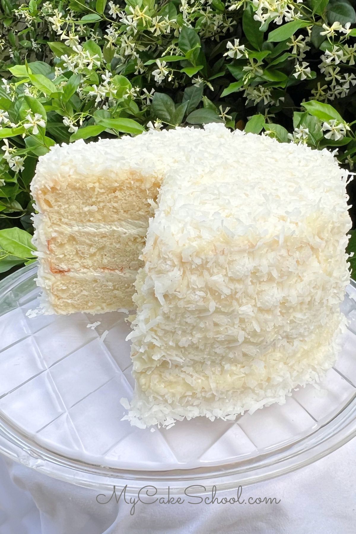 Easy Coconut Cake, sliced, on a cake pedestal.
