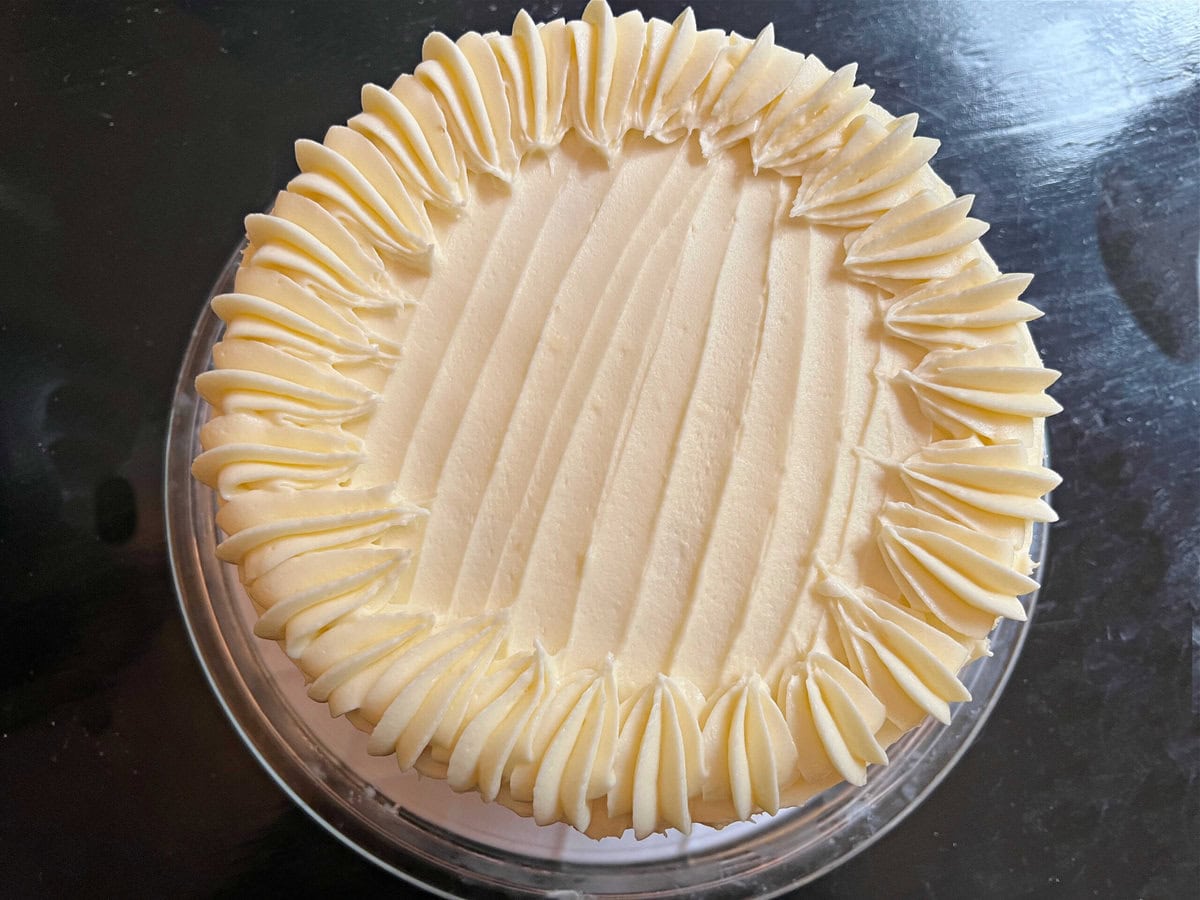 Decorating the top of the cake with piped shells of buttercream.