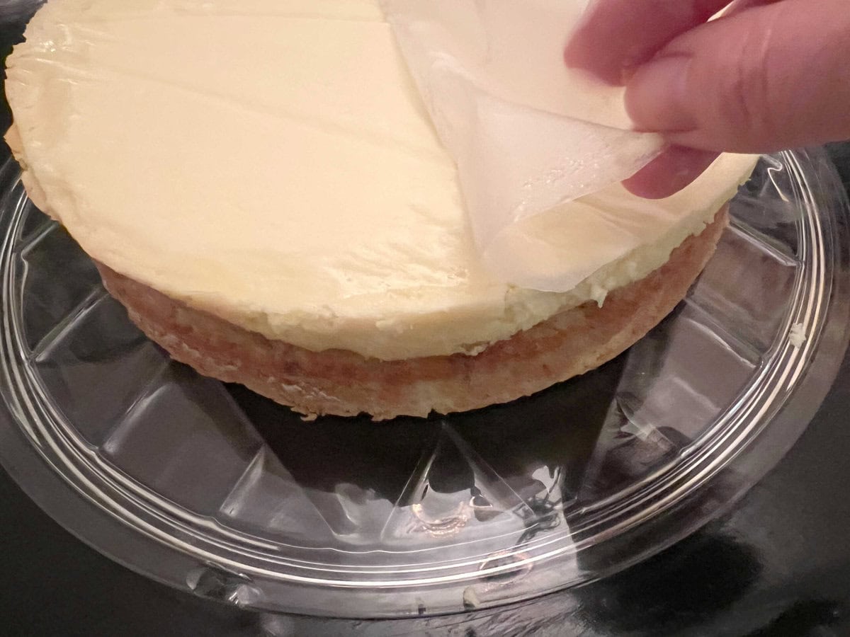 Peeling away parchment from cheesecake layer.