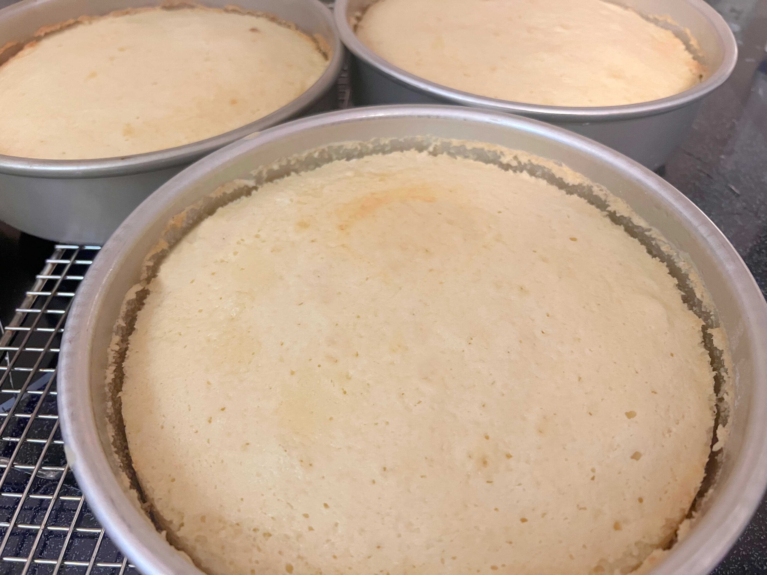 Freshly baked cake layers, cooling on a wire rack.
