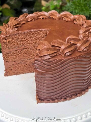 Moist Coca Cola Cake, sliced, on a cake pedestal.