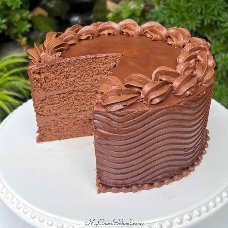 Moist Coca Cola Cake, sliced, on a cake pedestal.