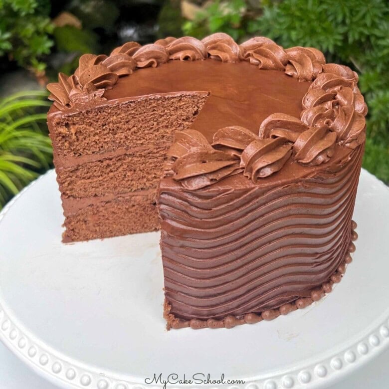 Moist Coca Cola Cake, sliced, on a cake pedestal.