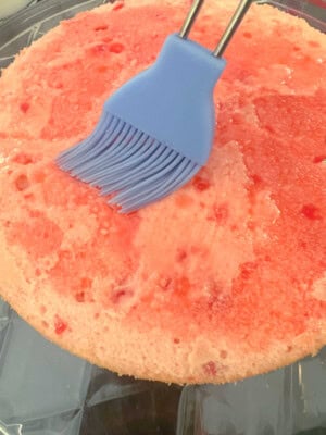 Glazing the cake layers with juice from the maraschino cherries jar.