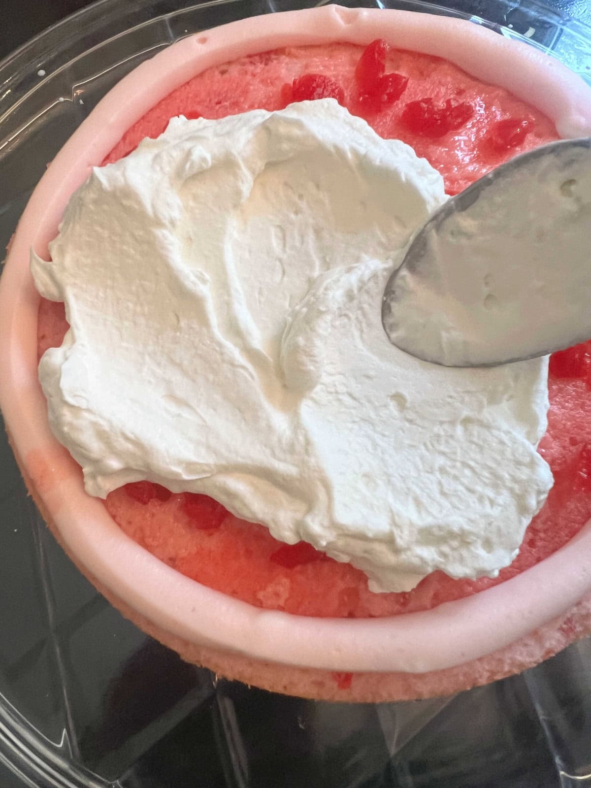 Filling the cherry velvet cake with glaze, cherries, and whipped cream.