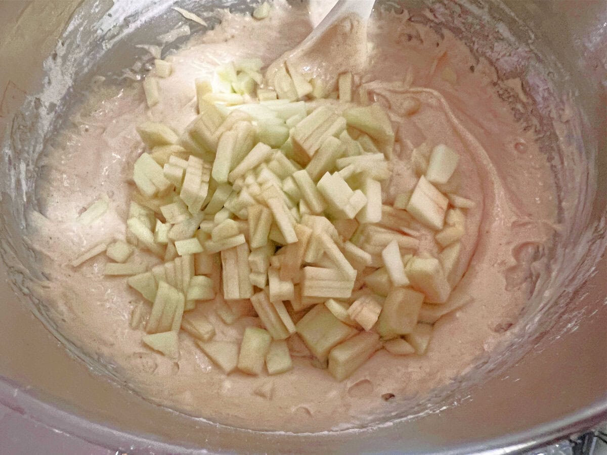 Folding apples into cake batter.