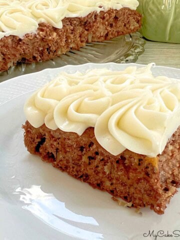 Slice of Apple Snack Cake on a plate, frosted with cream cheese frosting.