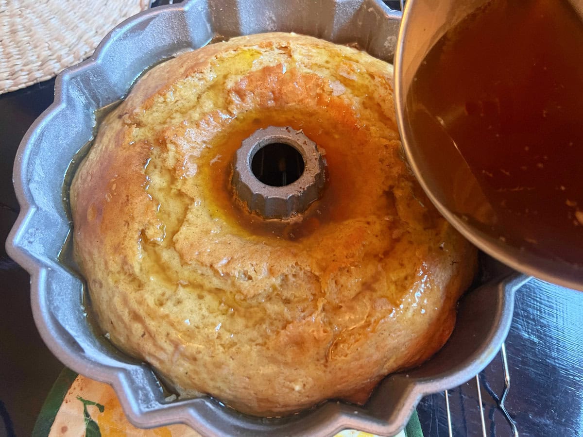 Pouring rum glaze over the freshly baked cake.