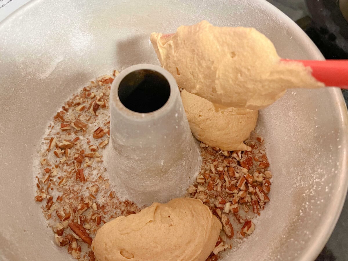 Scooping batter into the prepared bundt pan.
