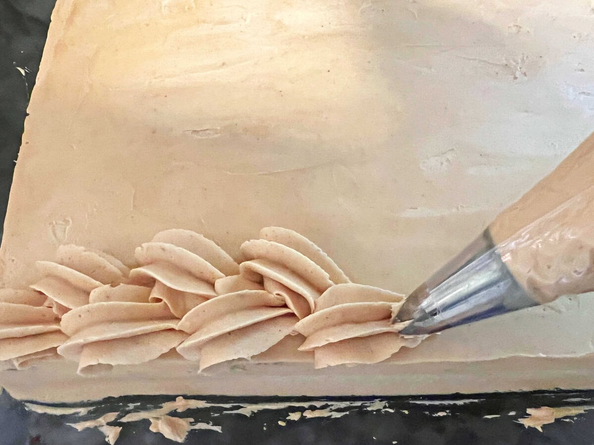 Piping a braided border on top of the cake.