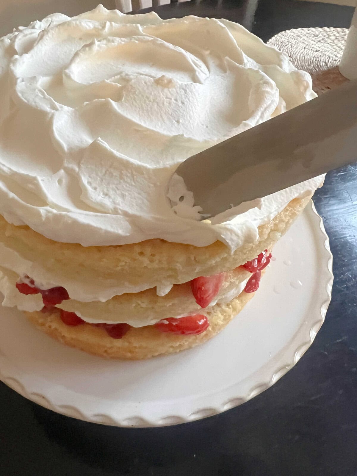 Spreading Whipped Cream on top of Cake.