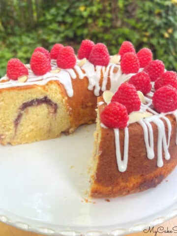 Raspberry Almond pound Cake, sliced, on a cake pedestal.