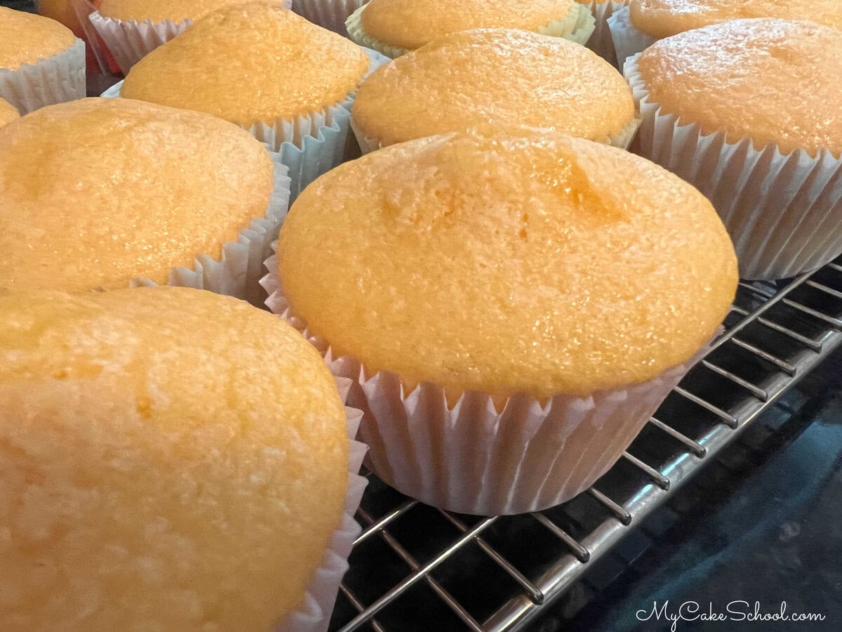 Orange cupcakes cooling on a cooling rack.