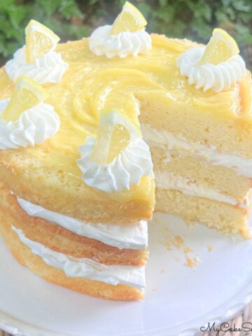 Layered Lemon Cream Cake, sliced, on a pedestal.
