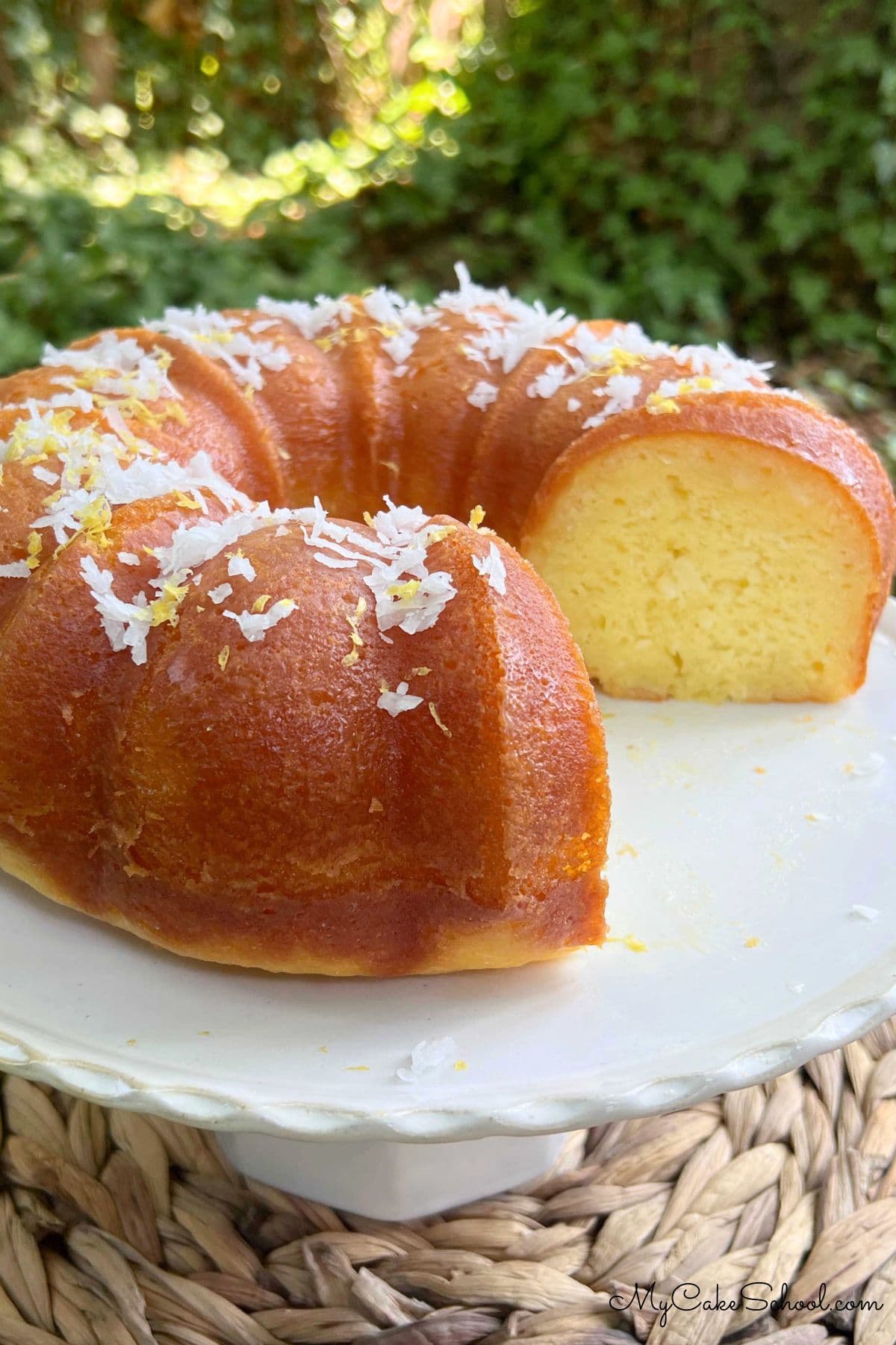 Moist and Rich Limoncello Coconut Bundt Cake on a cake plate, sliced.