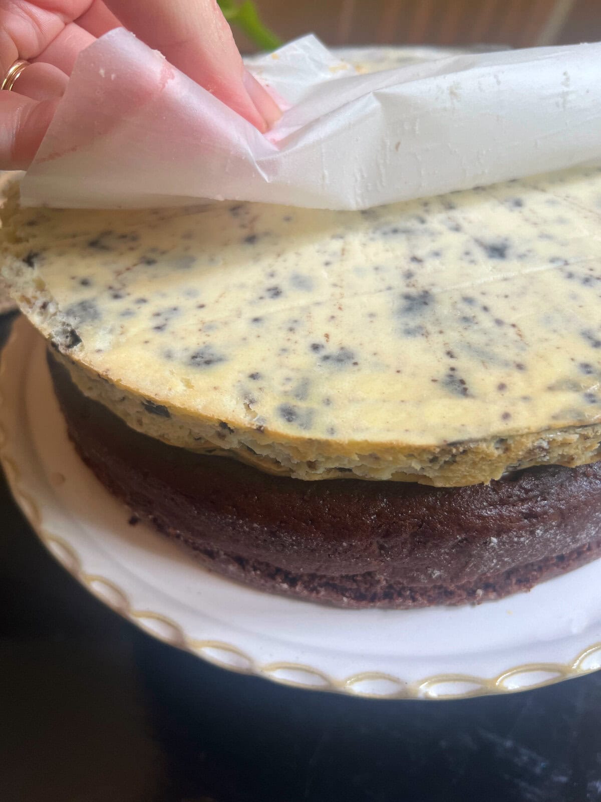 peeling the parchment from the cheesecake layer.