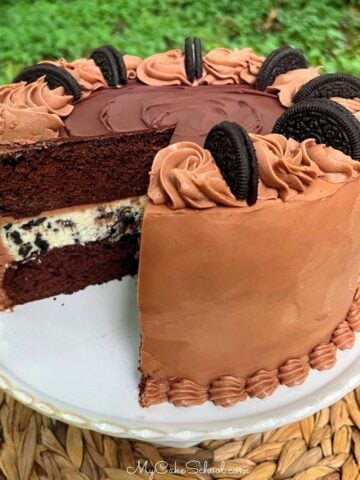 Oreo Cheesecake Cake, sliced on a pedestal.