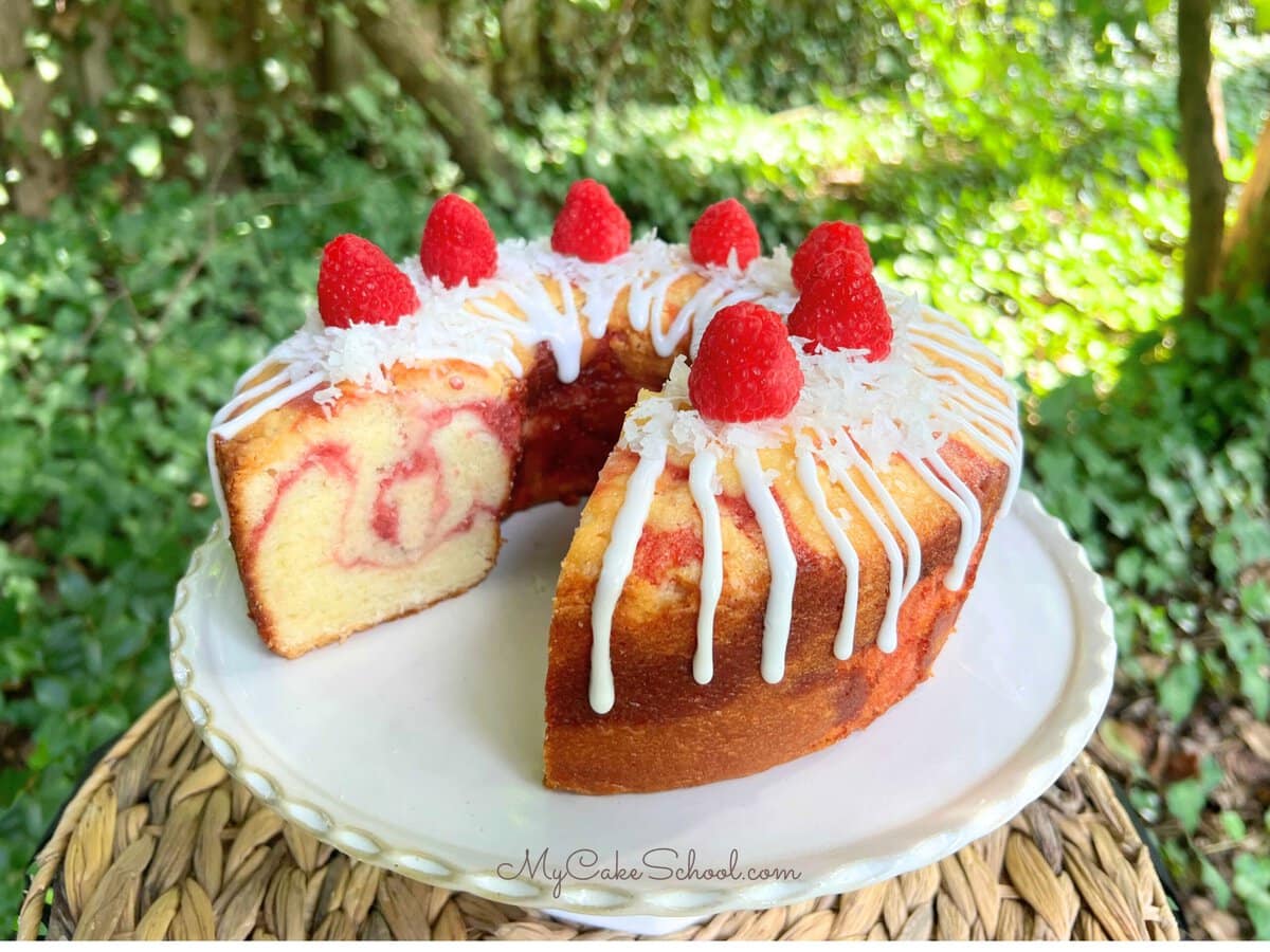 Coconut Raspberry Pound Cake, sliced, on a pedestal.