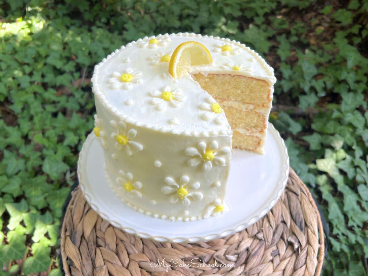 White Chocolate Lemon Cake, sliced, on a cake plate.